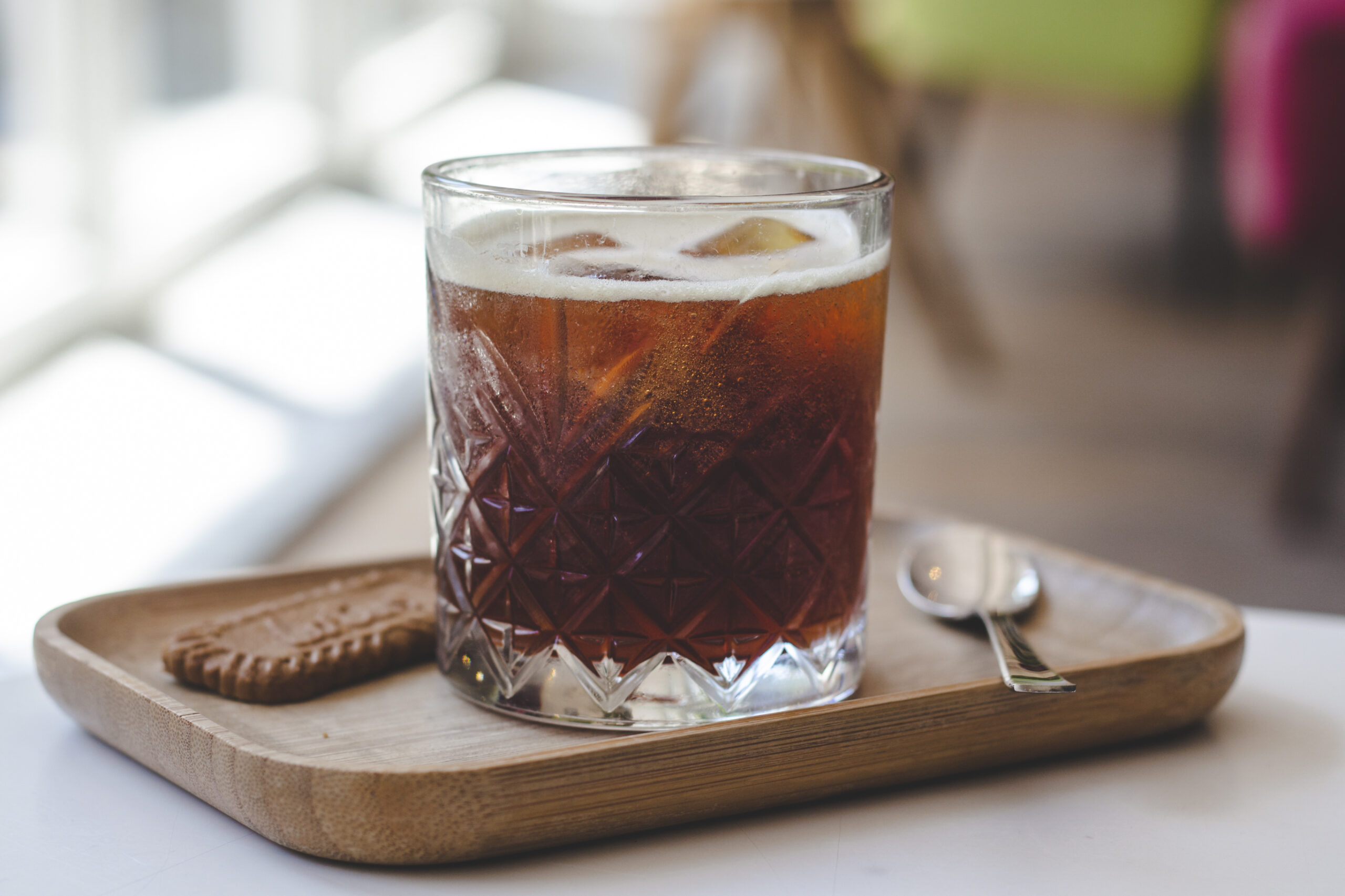 Cold brew nitro served over ice in a cut-glass tumbler with a cookie on the side